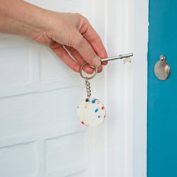 A person opening a door with a recycled plastic key chain.
