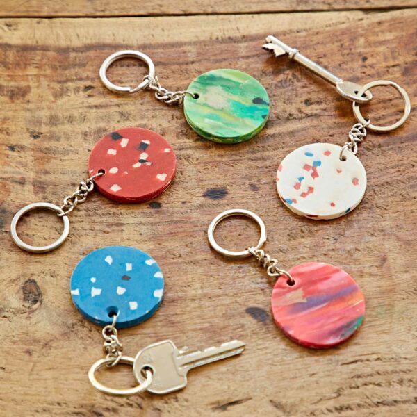 Five colourful Recycled Plastic Round Keyrings on a wooden table.