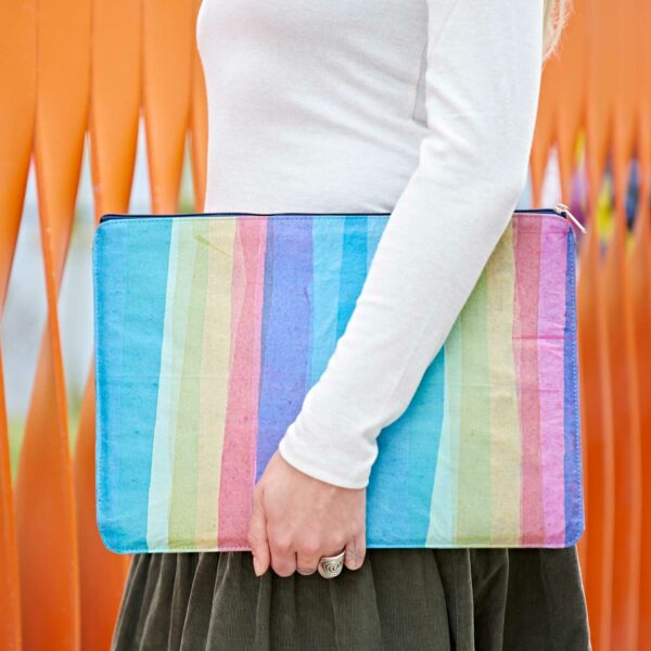 A woman holding a colorful Recycled Plastic Rainbow 16 inch Laptop Case.