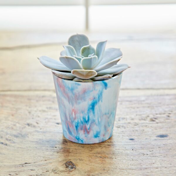 A mini planter with a succulent in it sitting on top of a wooden table.