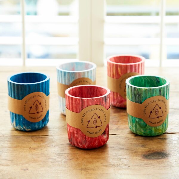 Five colorful Recycled Plastic Tumblers sitting on a wooden table.