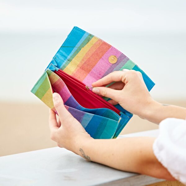 A woman holding a Recycled Plastic Rainbow Clutch Purse on the beach.