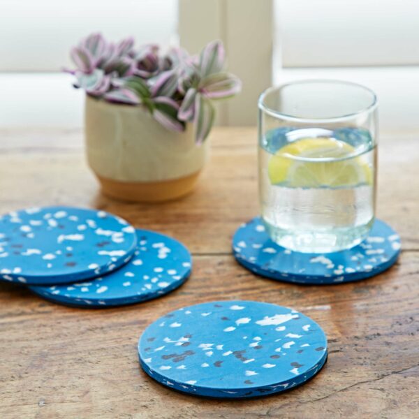 Round plastic coasters with blue splatter designs on a wooden table.