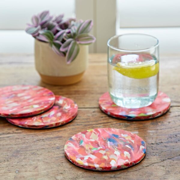 A set of recycled plastic coasters with a glass of water next to them.