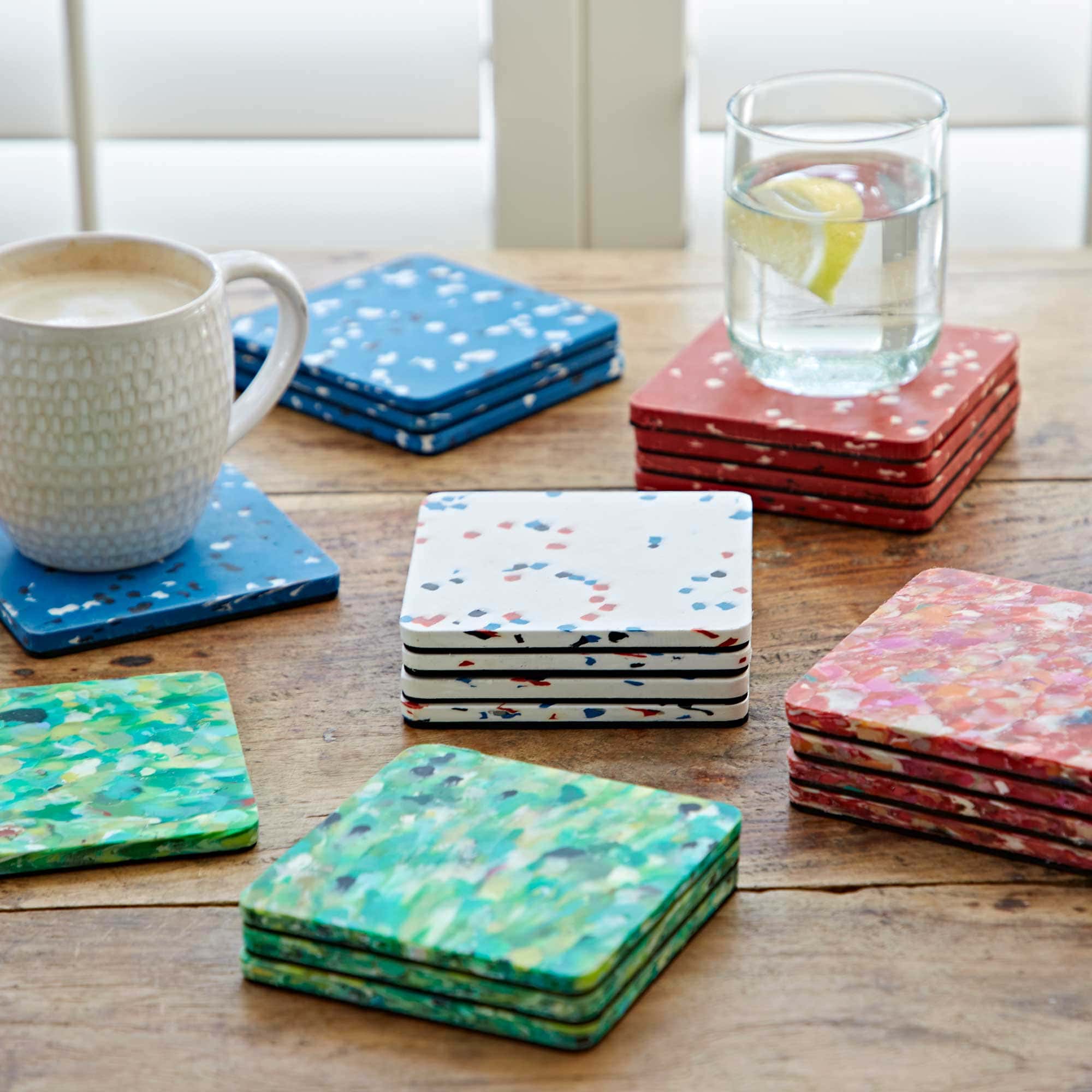 A set of 4 recycled round plastic coasters made from recycled plastic on a table with a cup of coffee.