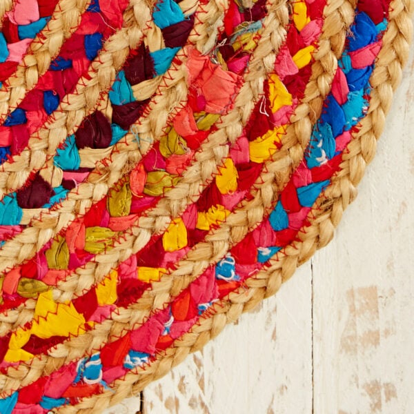 A Multicoloured Jute and Cotton Oval Rag Rug on a wooden surface.