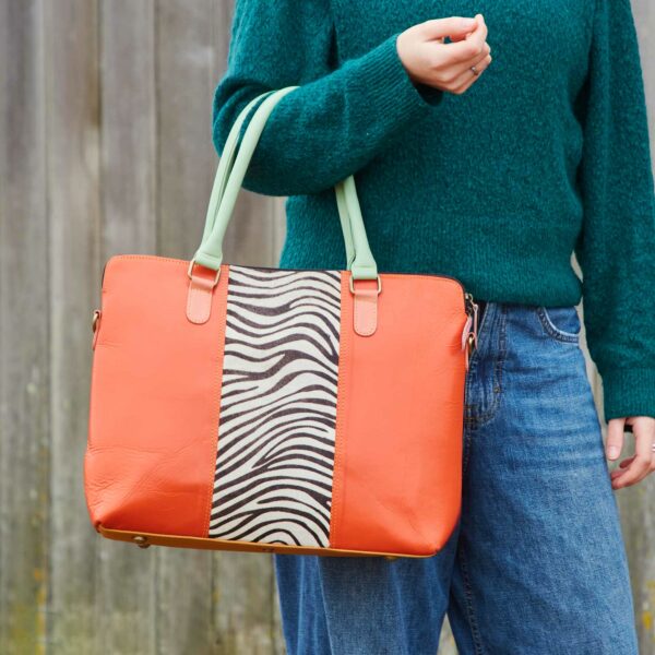 Kiara, a woman, holding an orange tote bag made from recycled leather.