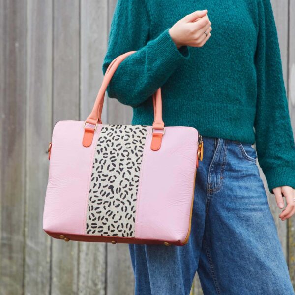 Kiara is holding a pink and leopard print bag made of recycled leather.