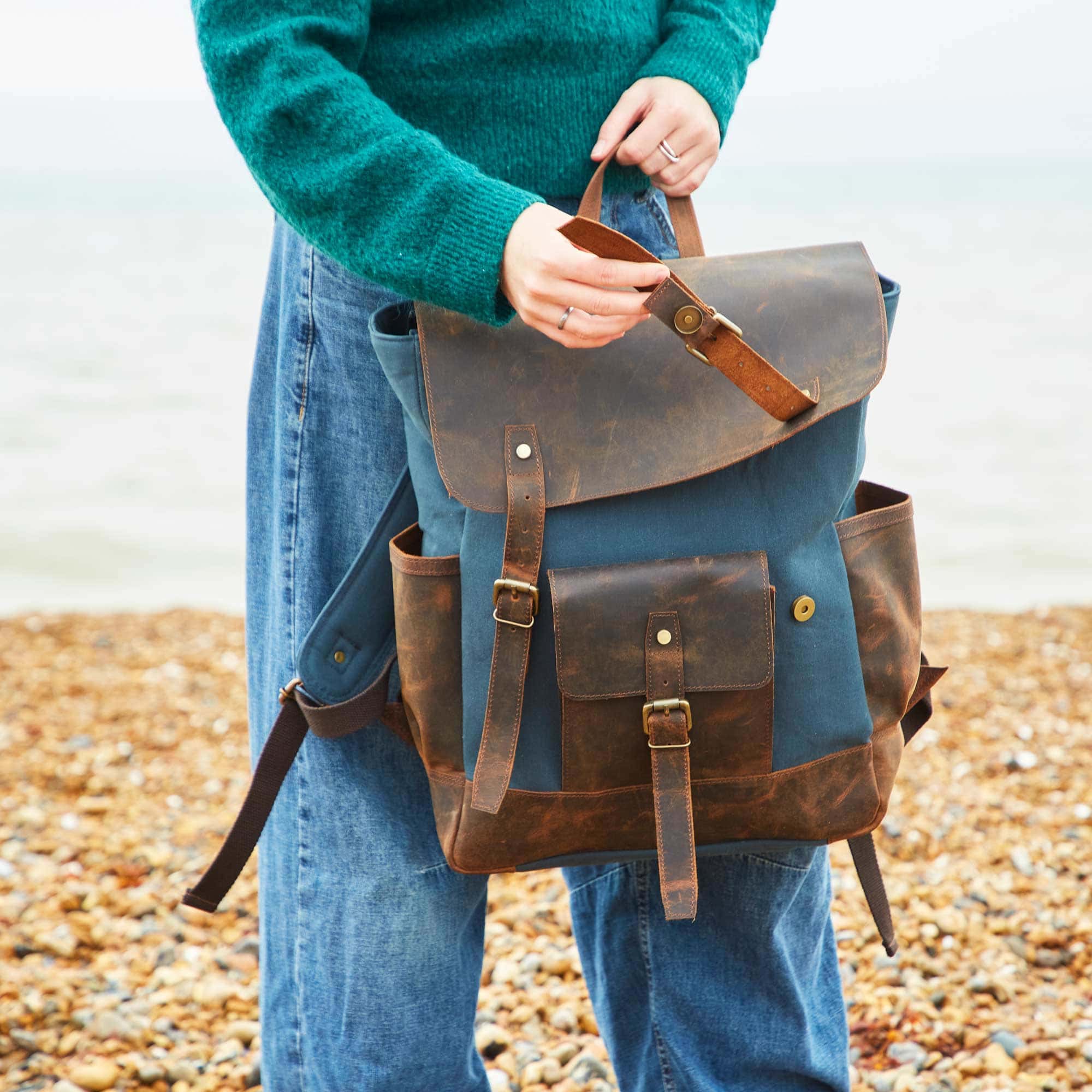 A woman holding a Personalised Black Canvas And Buffalo Leather Sling Bag (Copy) on the beach.