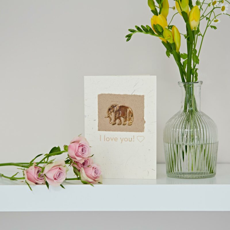 I love you elephant dung card with flowers and a vase on a shelf