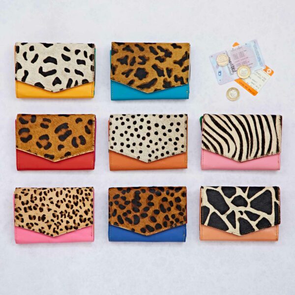 Nine Ananya Multicoloured Recycled Leather Purses are arranged in a grid pattern, showcasing their vibrant animal print elegance. Coins and cards are thoughtfully placed beside each stylish purse, completing the picture of everyday functionality with an eco-friendly twist.