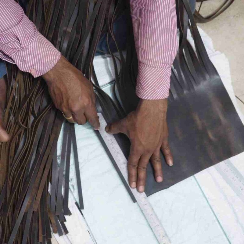 A man is working on a piece of leather, following a care guide.