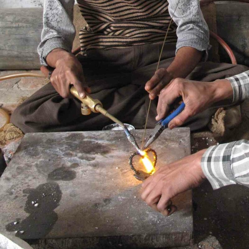 Two men working on a piece of metal as per a care guide.