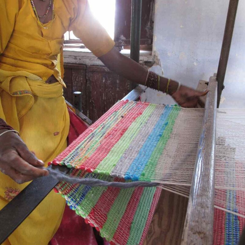 A woman is weaving on a loom, following a meticulous care guide.