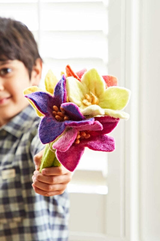 A young boy holding a bouquet of felt flowers as a Mother's Day gift.