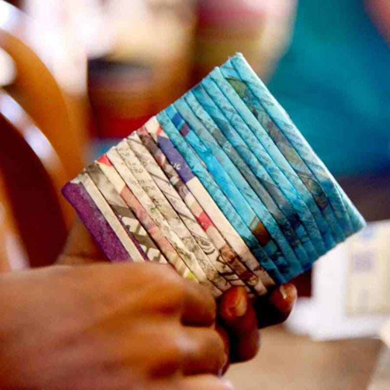A person holding up a wallet made out of paper, accompanied by a care guide.
