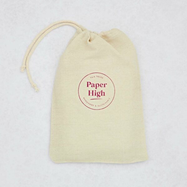 A beige drawstring cloth bag with "Paper High" printed in red at the center, alongside the phrases "Fair Trade," "Handcrafted & Sustainable," perfect for carrying your cherished Tree of Life Buffalo Leather Journal with Gemstones.