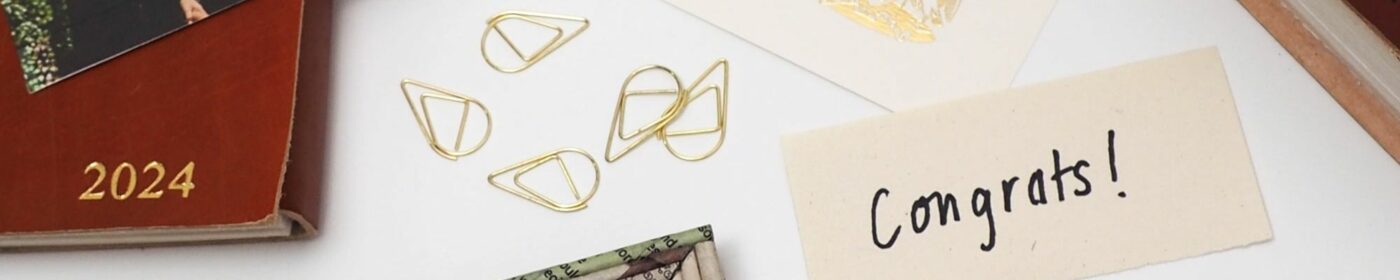 2024 planner, gold paper clips, a card with artwork, and a note saying "Congrats!"—all displayed on a white surface. Featured in the Fair Trade Father's Day Gift Guide for those seeking thoughtful gifts.