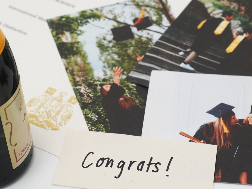 Graduation-themed items including photos of graduates in caps and gowns, a letter, and a "Congrats!" note are displayed, accompanied by a bottle—perfect ideas you might find in our Fair Trade Father's Day Gift Guide.