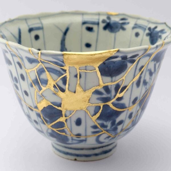 A ceramic bowl with blue floral patterns, repaired with golden seams using the Japanese art of Kintsugi, mirrors the experience of a Wild Beaver on a River Stour Canoe Tour and Talk.