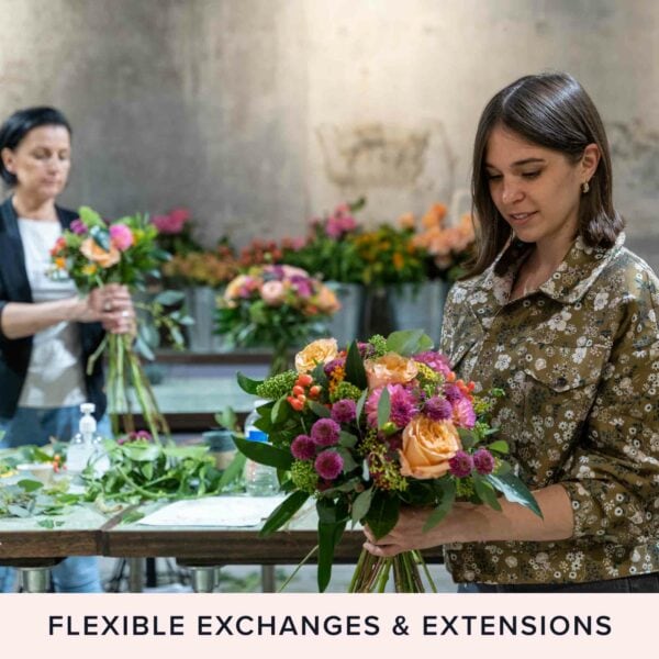 Two women arranging colorful flower bouquets in a workshop. A sign below reads "FLEXIBLE EXCHANGES & EXTENSIONS." The scene is serene and reminiscent of the tranquility found in Goat Yoga for Two in the Suffolk Countryside.