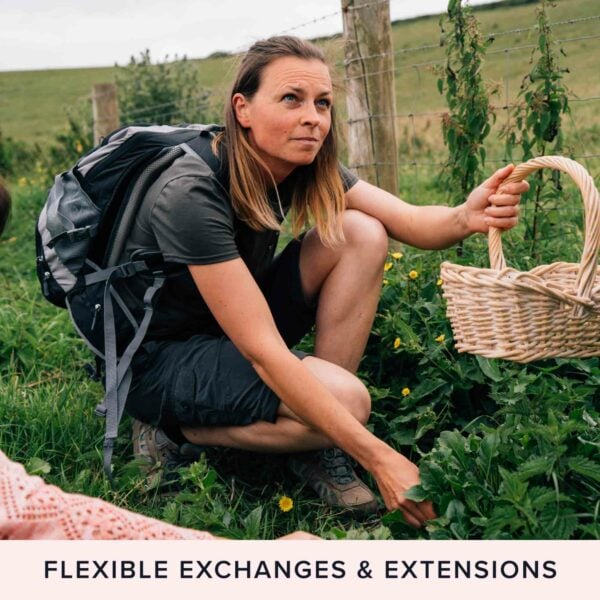 A person wearing a backpack crouches in a grassy field, holding a woven basket and picking plants with a focused expression. Text at the bottom reads "Totally Wild Foraging, Cookery and Lunch for Two - Flexible Exchanges & Extensions.