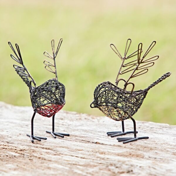 The Set of Two Wire Robin with Wings Decorative Ornament features wire bird sculptures with paperclip wings on a wooden surface, set against a blurred grassy background for an enchanting effect.