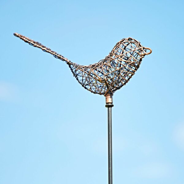 A Metal Bee Garden Stake Ornament perches gracefully on a garden stake, silhouetted against a clear blue sky.