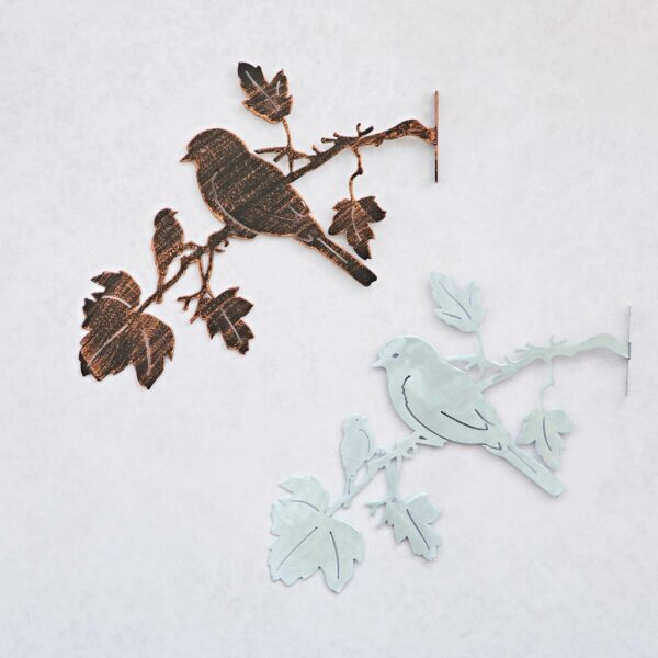 Recycled Iron Bird Silhouette Garden Art showcases two birds—one dark rust, one light blue—perched on a branch and mounted on a plain white background, making an elegant metal wall piece.