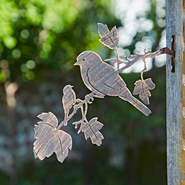The Recycled Iron Bird Silhouette Garden Art features two birds perched on a leafy branch, mounted on a wooden post with a softly blurred garden backdrop.