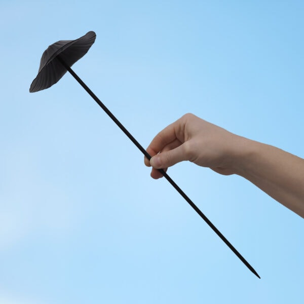 A hand displays the Recycled Metal Mushroom Garden Stake—a striking copper ornament made from recycled metal—set against a clear blue sky.