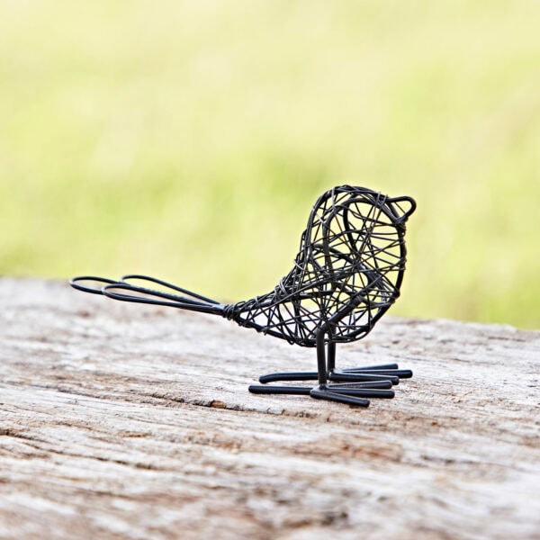 A Set of Two Wire Robins with Wings Decorative Ornament gracefully perches on a wooden surface against a blurred green background.