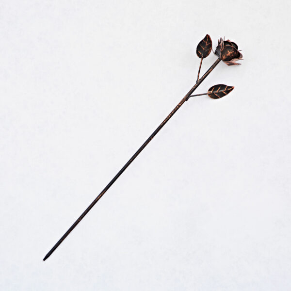 The Recycled Iron Distressed Copper Rose Garden Stake features a metallic rose with two leaves on a long stem, crafted from recycled iron and shown against a white background—ideal as a unique garden accent.
