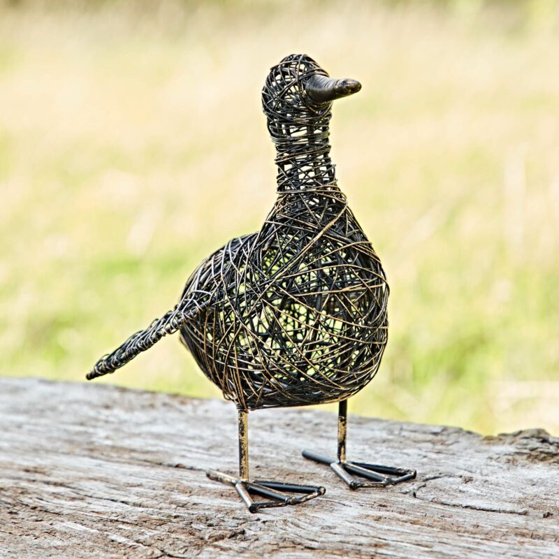 Anka the Drinking Duck Wire Garden Ornament features a rounded body and long tail, standing elegantly on a textured wooden surface. Against a blurred background, it beautifully captures the essence of nature.