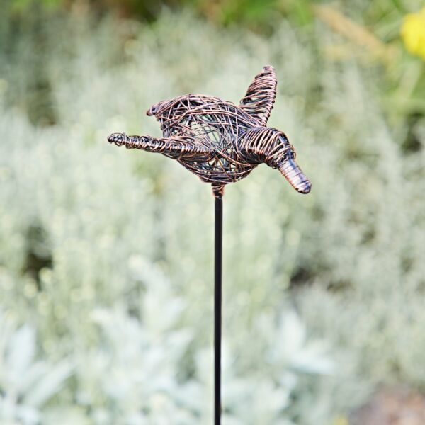 The Recycled Wire Duck Garden Stake Decoration features a duck crafted from recycled wire, mounted on a slim metal rod and perfect as an eye-catching garden accent against outdoor greenery.