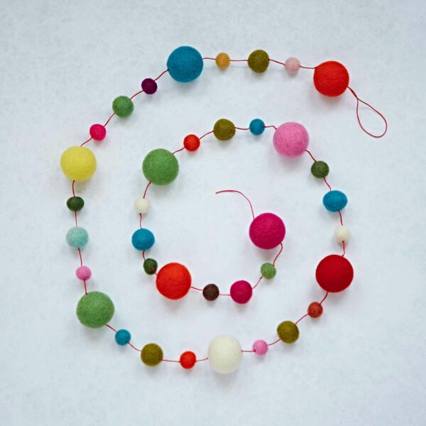 The Felt Small and Large Ball Garland, spiraled on a light surface, features vibrant red, pink, green, yellow, blue, and orange balls in various sizes for a lively decor touch.