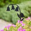 A Recycled Metal Echinacea Silhouette Garden Stake in black stands among blooming pink flowers and green foliage with a blurred background.