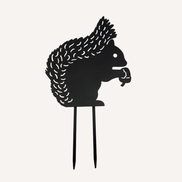 The Recycled Metal Squirrel Silhouette Garden Stake features a charming squirrel holding an acorn and includes two pointed prongs for easy placement in your garden.
