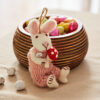 A Felt Rabbit with Mushroom Hanging Decoration adds charm to the scene, sitting by a wooden bowl of colourful sweets and small speckled eggs scattered on the table.
