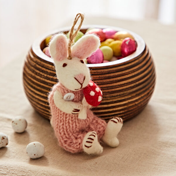 A Felt Rabbit with Mushroom Hanging Decoration adds charm to the scene, sitting by a wooden bowl of colourful sweets and small speckled eggs scattered on the table.