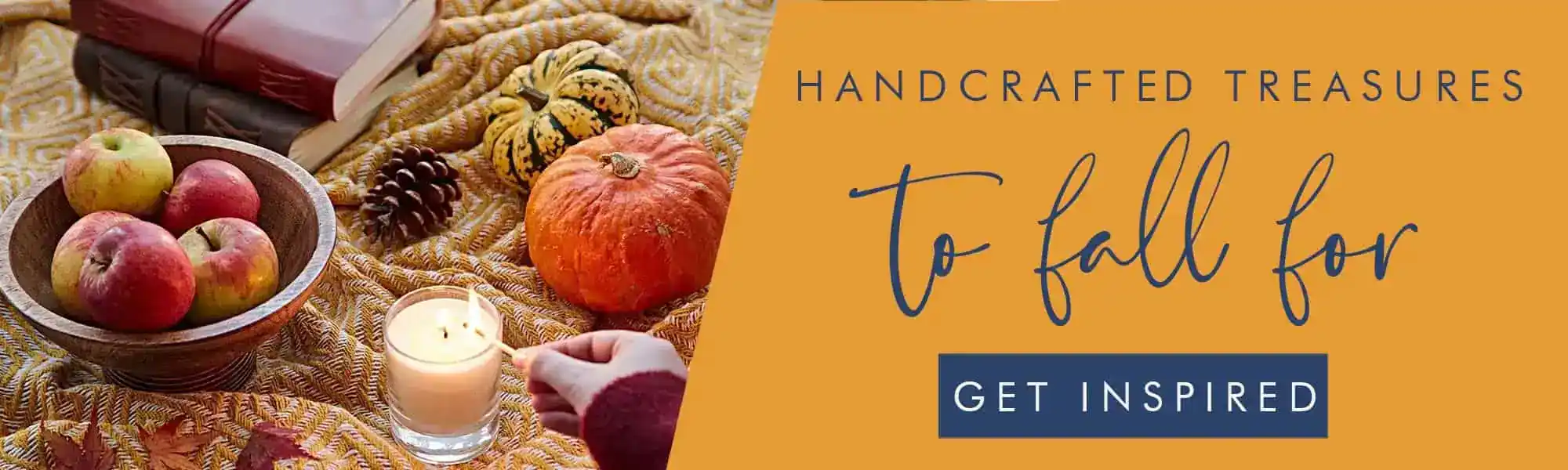 A hand reaches for a lit candle on a blanket beside apples in a bowl, a pumpkin, pine cones, a book from Paper High, and decorative gourds. Text reads: "Handcrafted treasures to fall for. Get inspired.