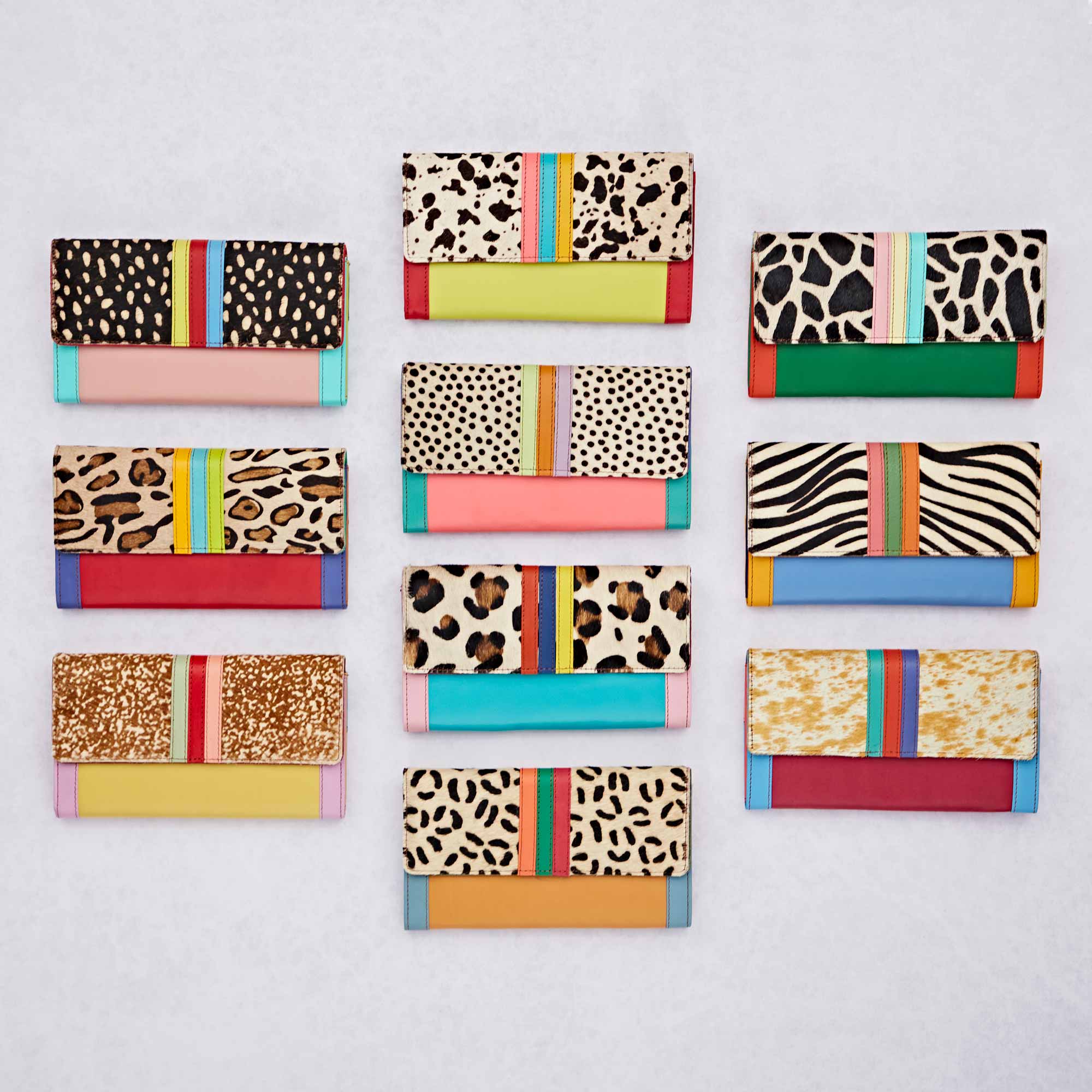 Twelve Hema Multicoloured Recycled Leather Clutch Purses with animal prints and colourful stripes are arranged in three rows on a light background.