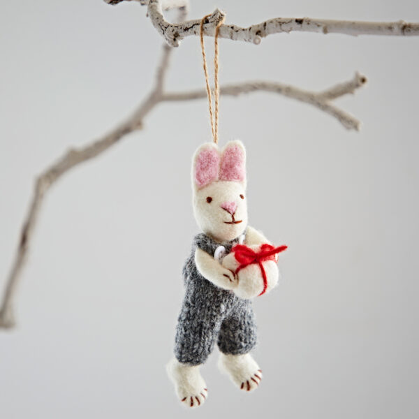 The Felt Rabbit with Gift Hanging Decoration features pink ears, a grey outfit, and holds a red and white present, making it a charming addition to any tree or branch.