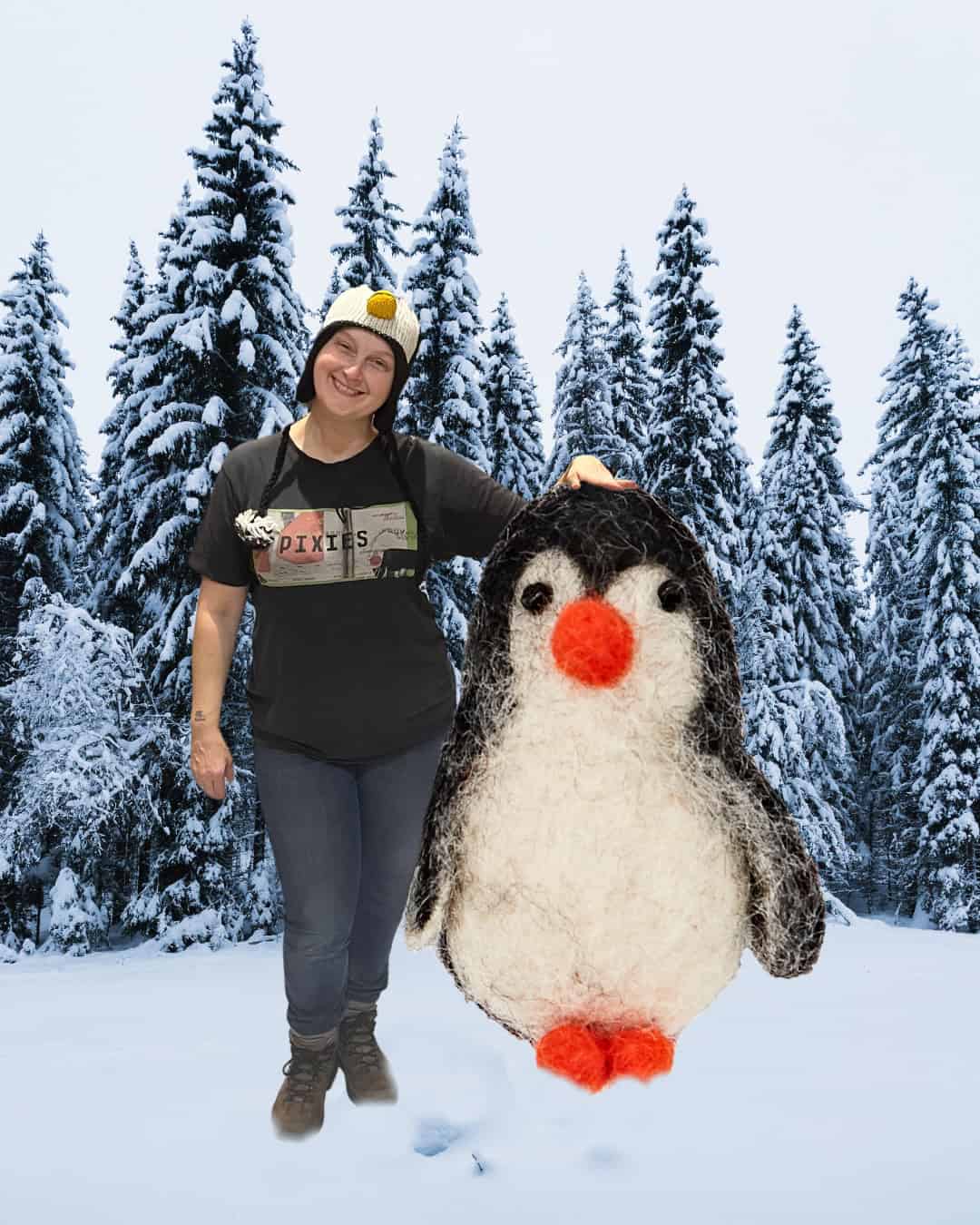 A person in a penguin hat stands in snow next to a large stuffed penguin, with snow-covered trees in the background—one of our Staff Favourites for Christmas.