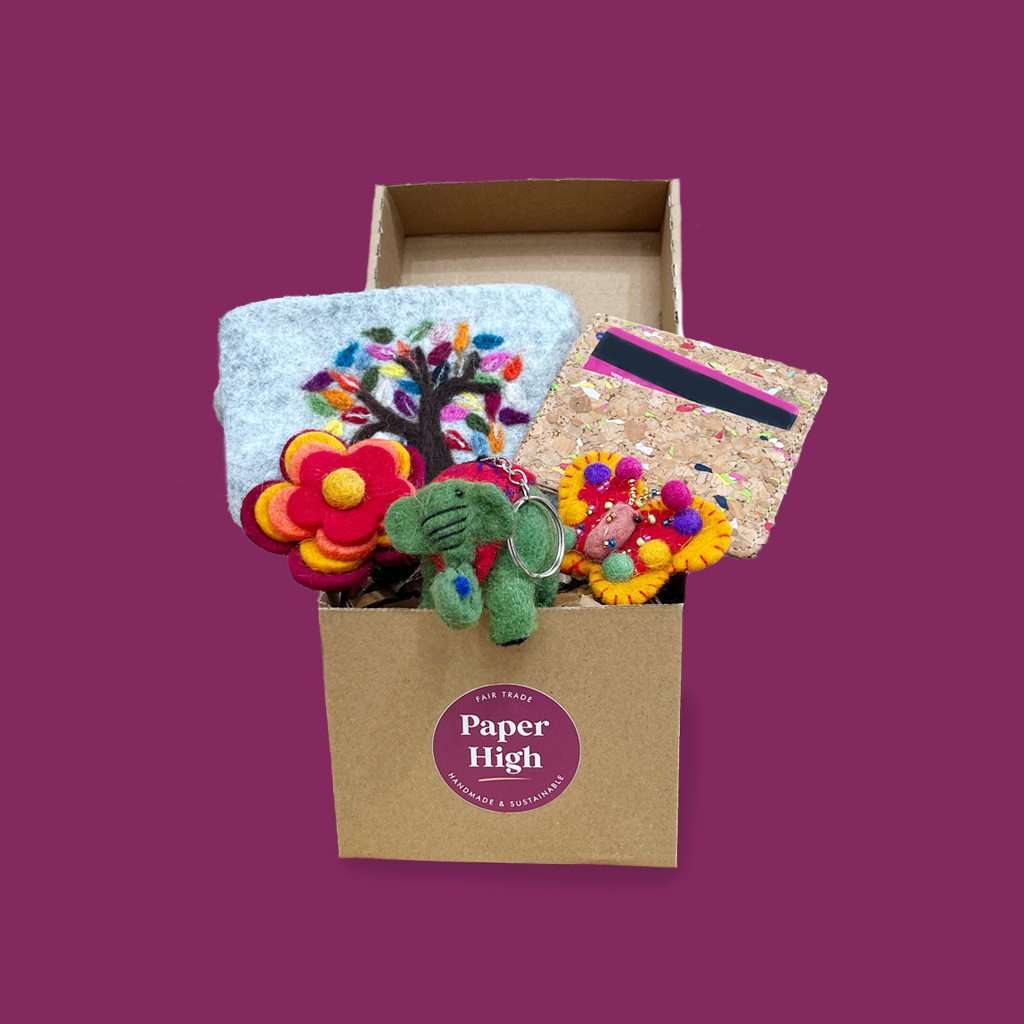 A cardboard box labelled "Paper High" contains colourful felt accessories, a cork-covered notebook, a card, and an Antique Brass Candle Lantern (Copy), all set against a plain purple background.