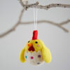 The Felt Chick in Egg Hanging Decoration features yellow wings, a red crest, and hangs from a white string on a bare twig.