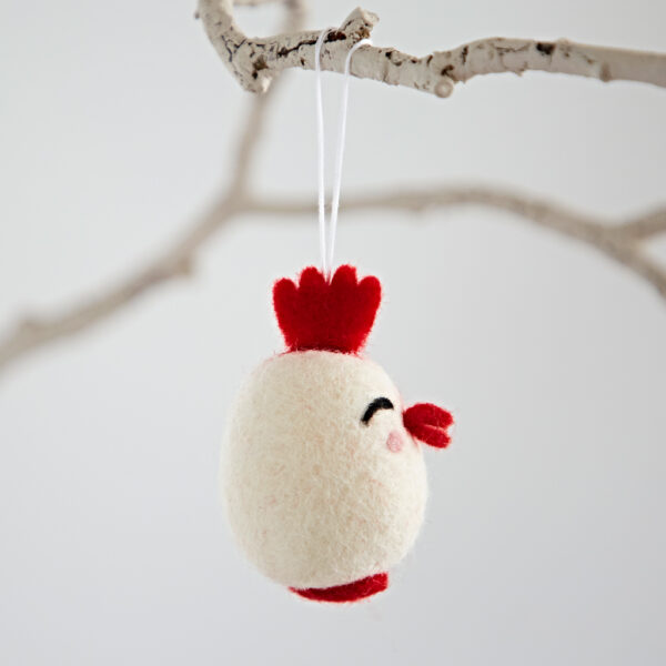The Felt Easter Chick Hanging Decoration, shaped like a chick, hangs by a white string from a branch against a plain background.