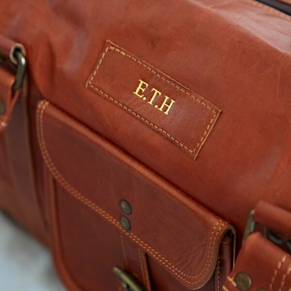 Close-up of the Personalised Brown Leather Holdall with Zipped Pockets, showcasing gold-embossed
