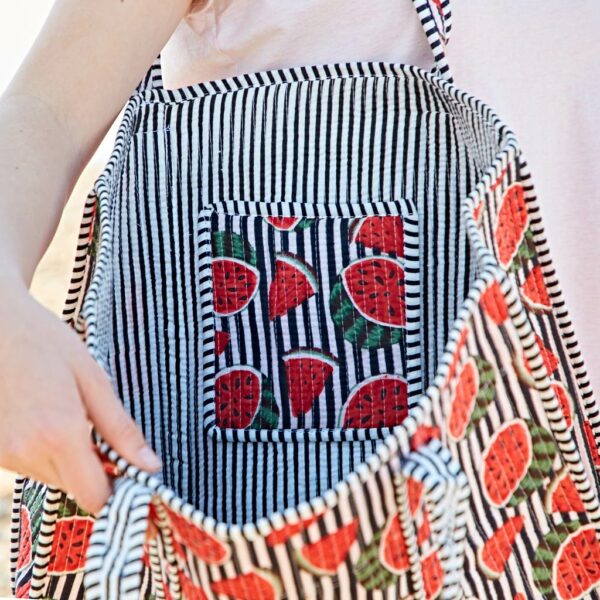 A person holds open a black-and-white striped bag with a watermelon print design on the outer and inner pocket fabric.