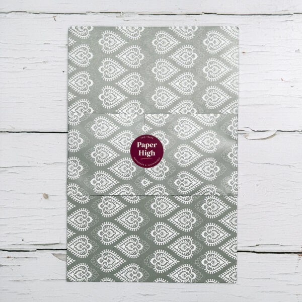 A grey envelope featuring a white paisley pattern and sealed with a maroon circular 